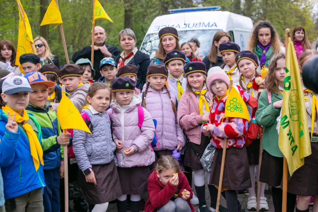Діти у скаутській формі тримають жовті прапорці