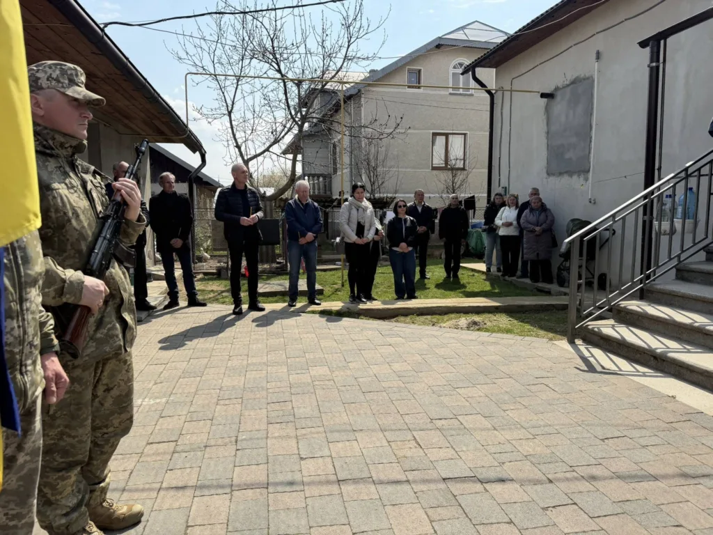 Військовий із прапором перед громадянами на подвір’ї