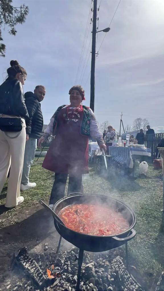 Жінка готує борщ у казані на вогнищі