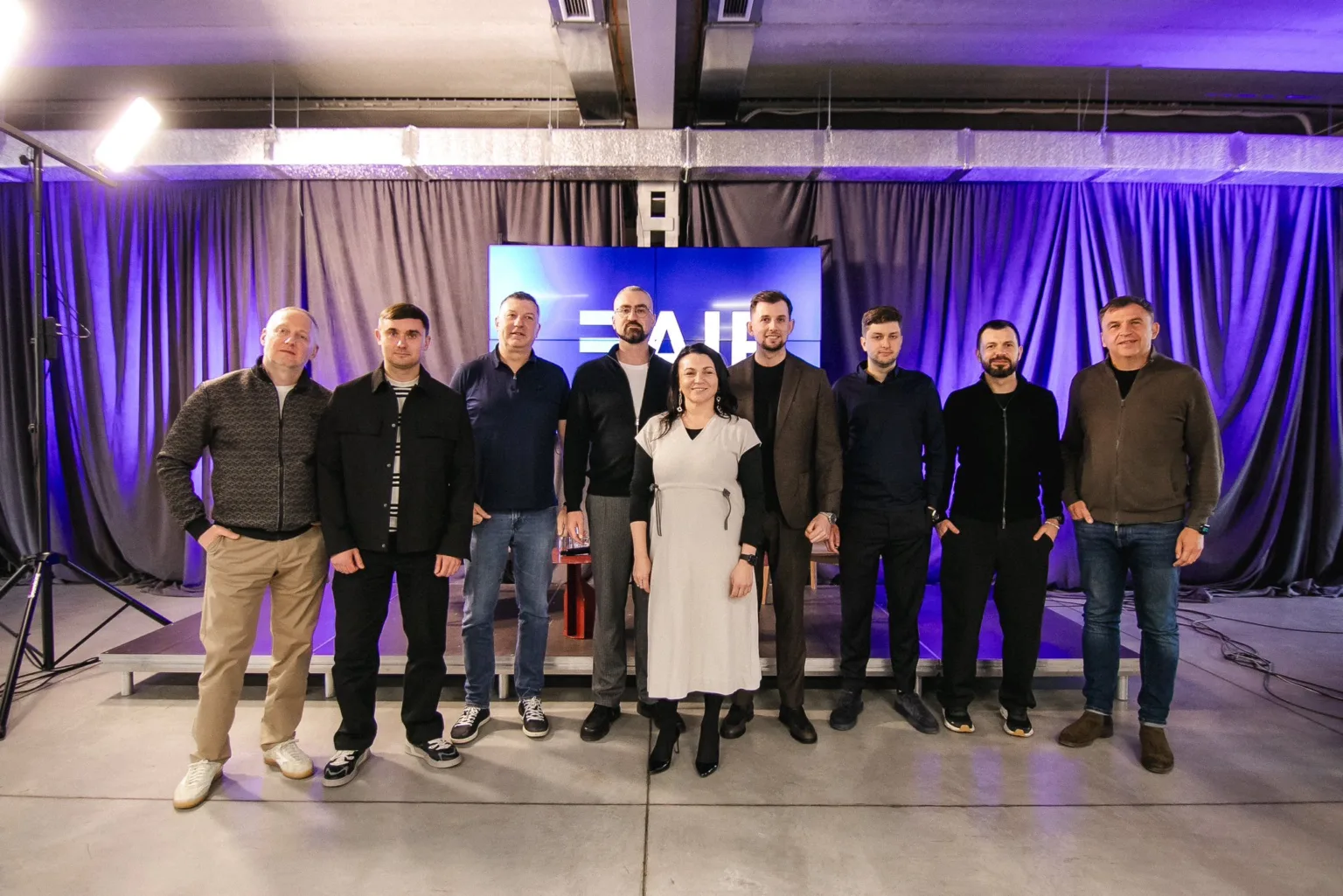 Група людей на сцені перед фіолетовою завісою