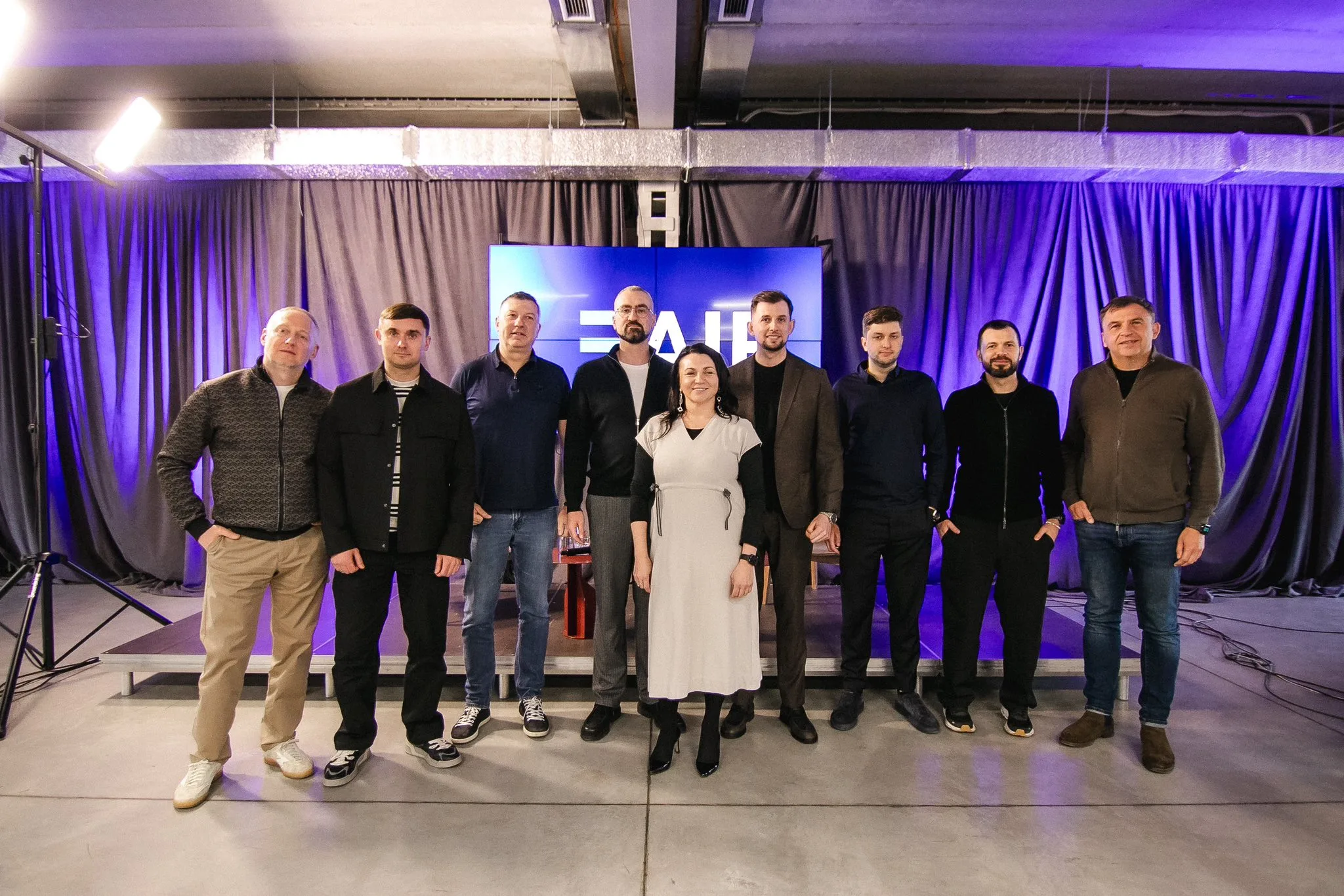 Група людей на сцені перед фіолетовою завісою