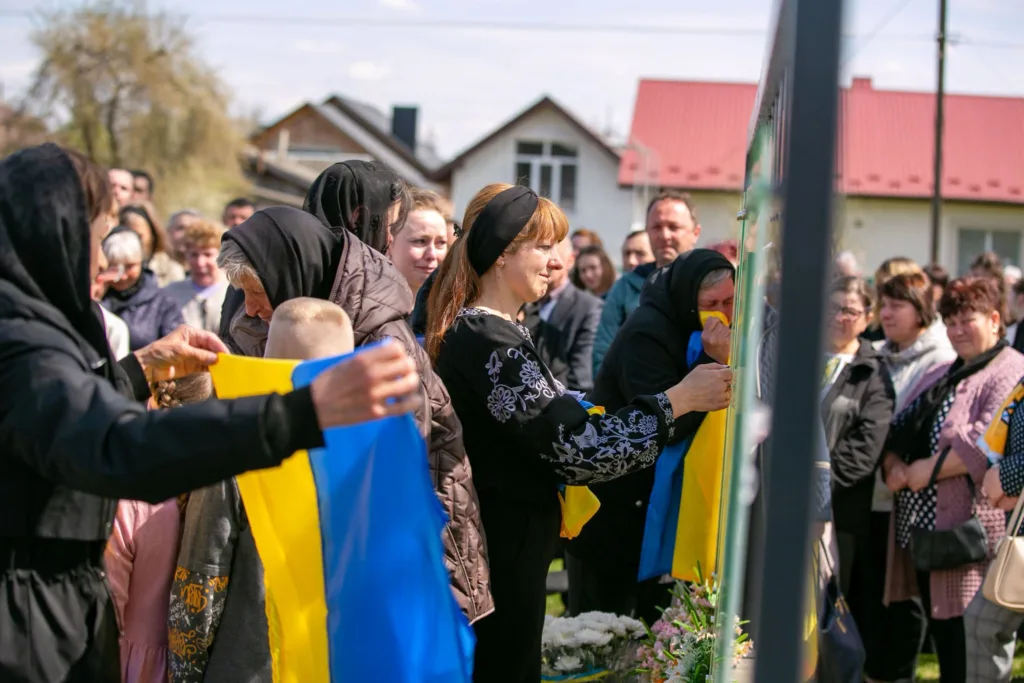 Люди з українськими прапорами на меморіальній церемонії