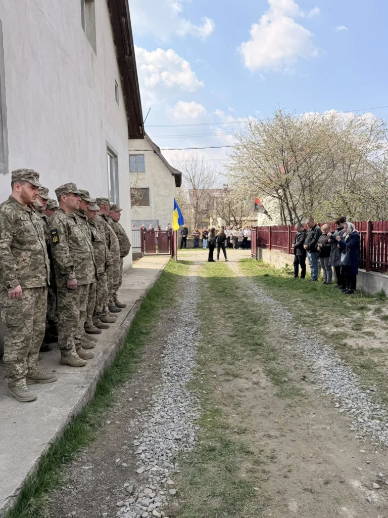 Військові стоять на подвір’ї біля прапора України