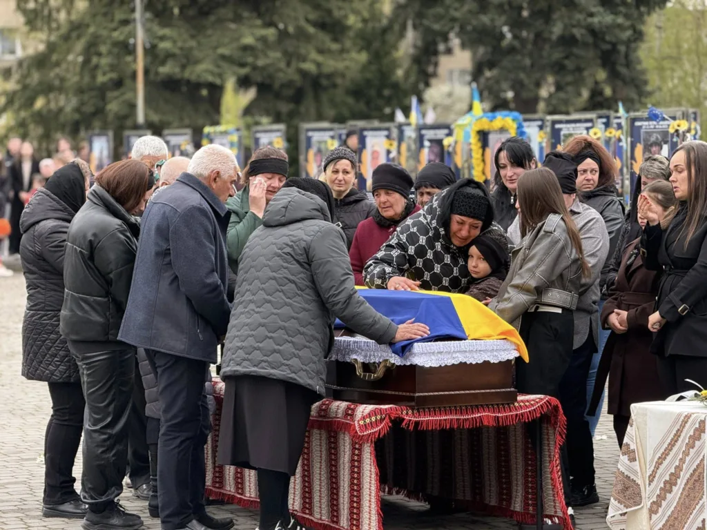 Люди прощаються з полеглим героєм під українським прапором
