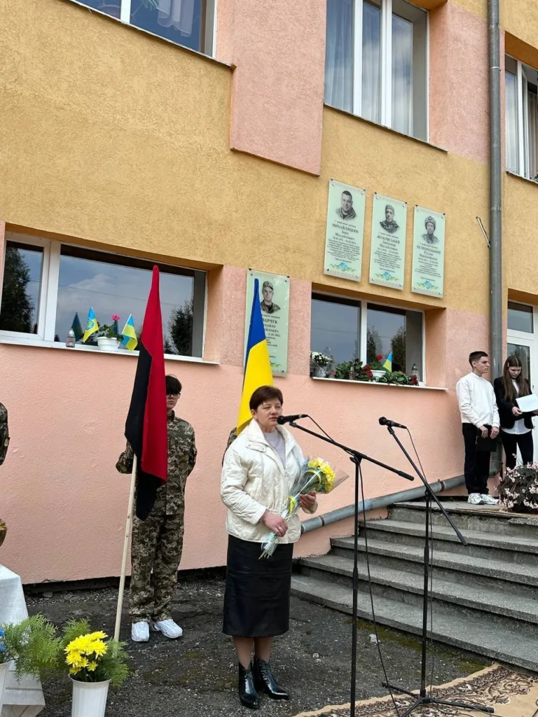 Жінка з квітами виступає перед школою в Україні