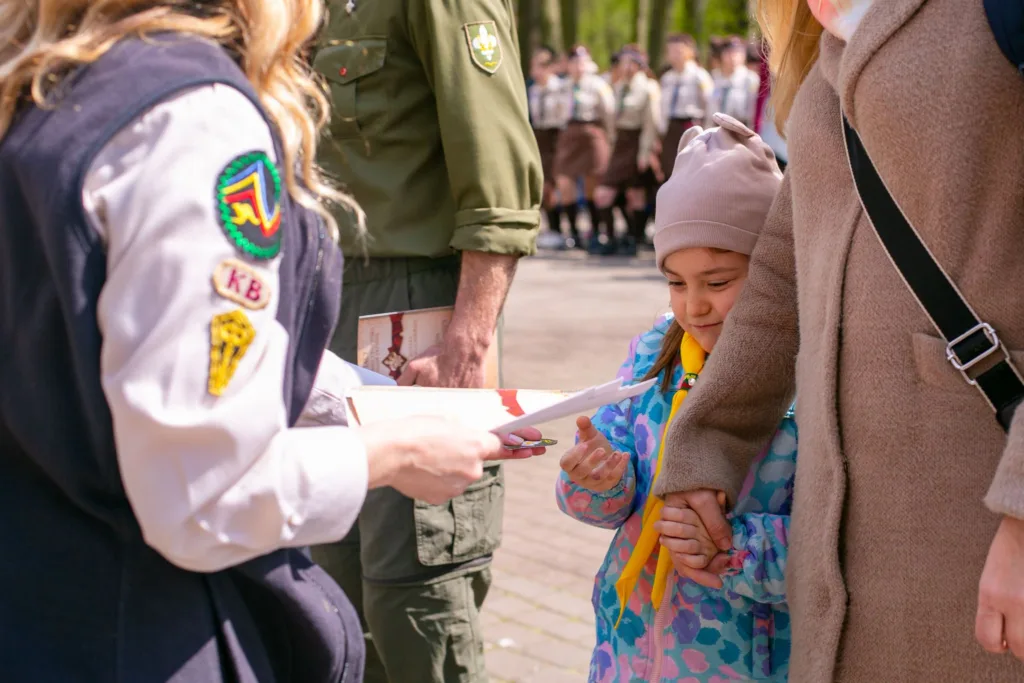 Дитина отримує документ від скаута на церемонії