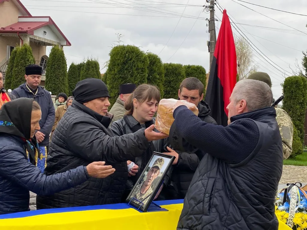 Прощання з військовим, люди тримають хліб і фото