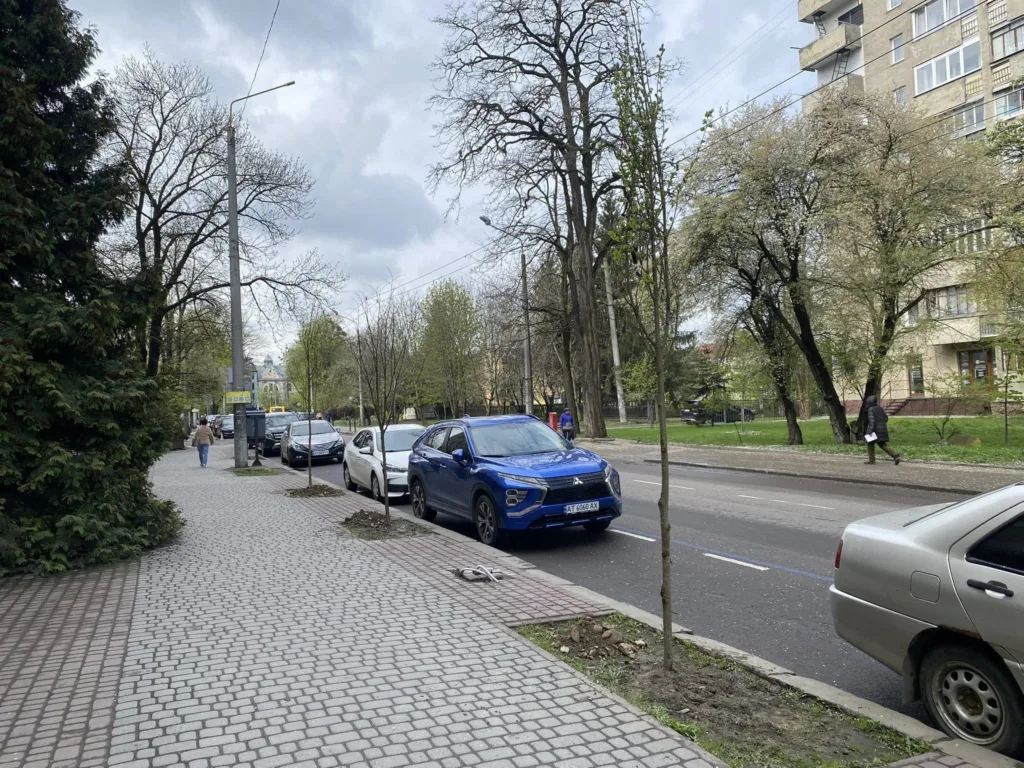 Міська вулиця з припаркованими автомобілями та деревами