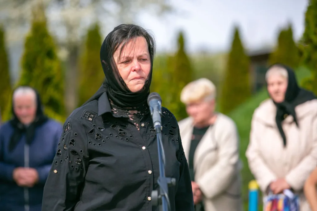 Жінка у чорній хустці говорить біля мікрофона