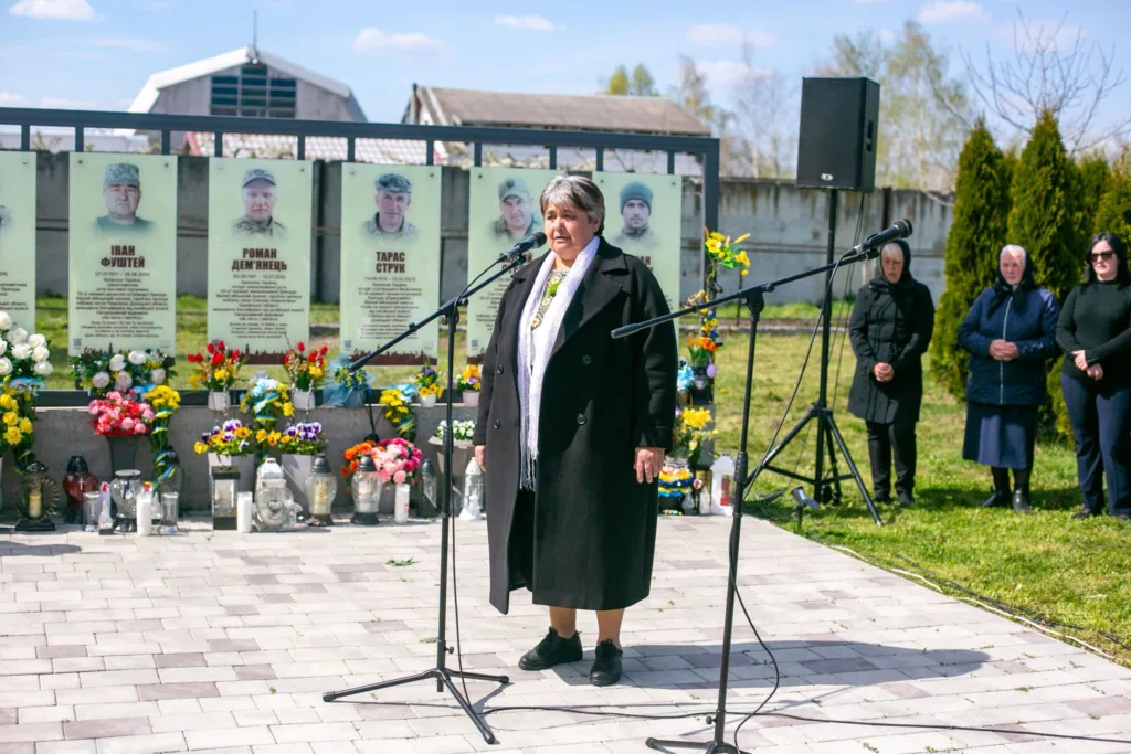 Жінка виступає біля меморіалу загиблим військовим