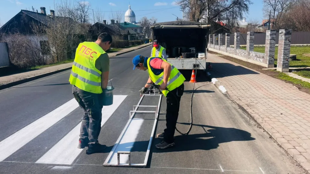 Робітники наносять розмітку пішохідного переходу на дорозі