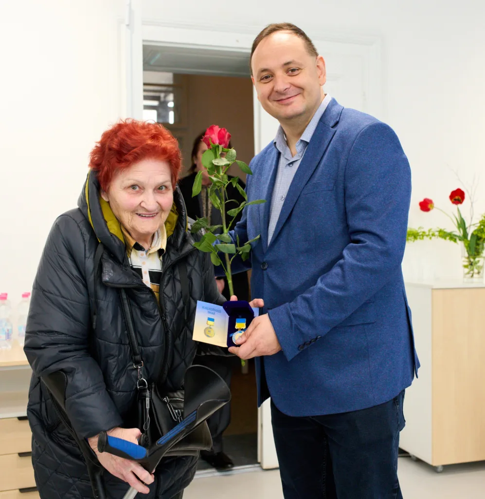 Жінка отримує квітку та медаль від чоловіка