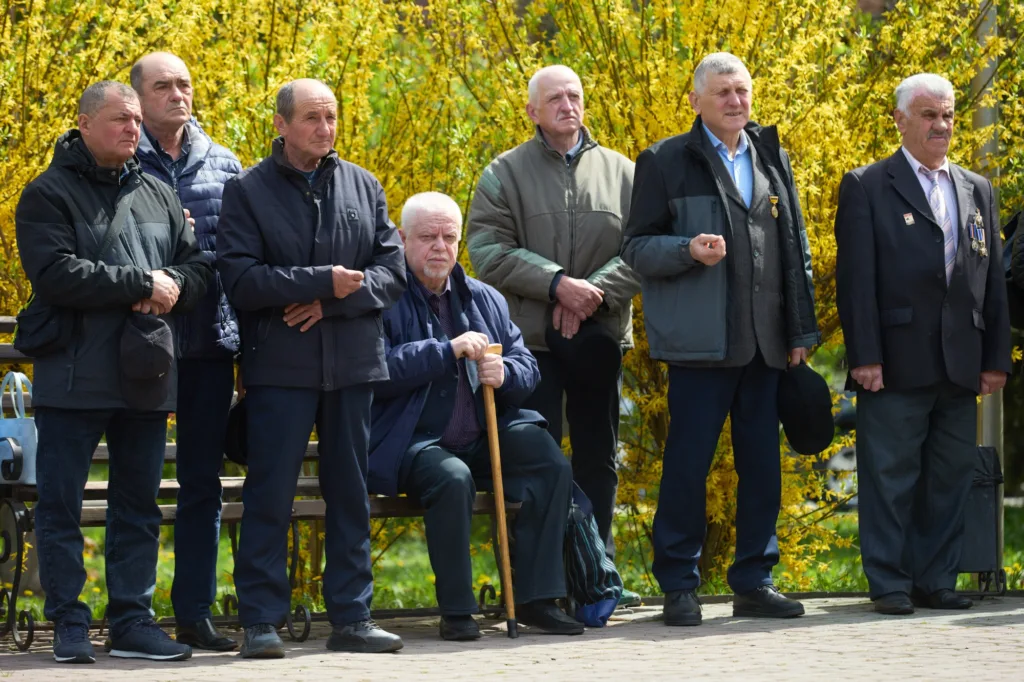 Група літніх чоловіків стоїть біля лавки у парку