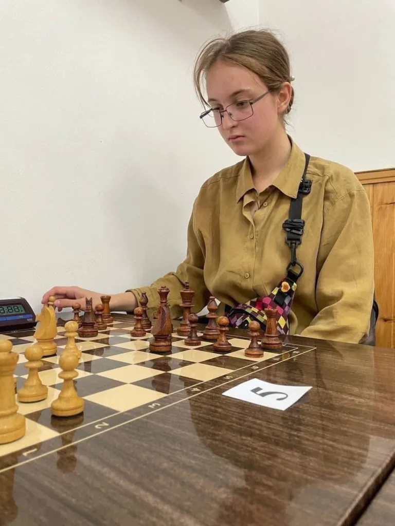 Дівчина грає в шахи за столом