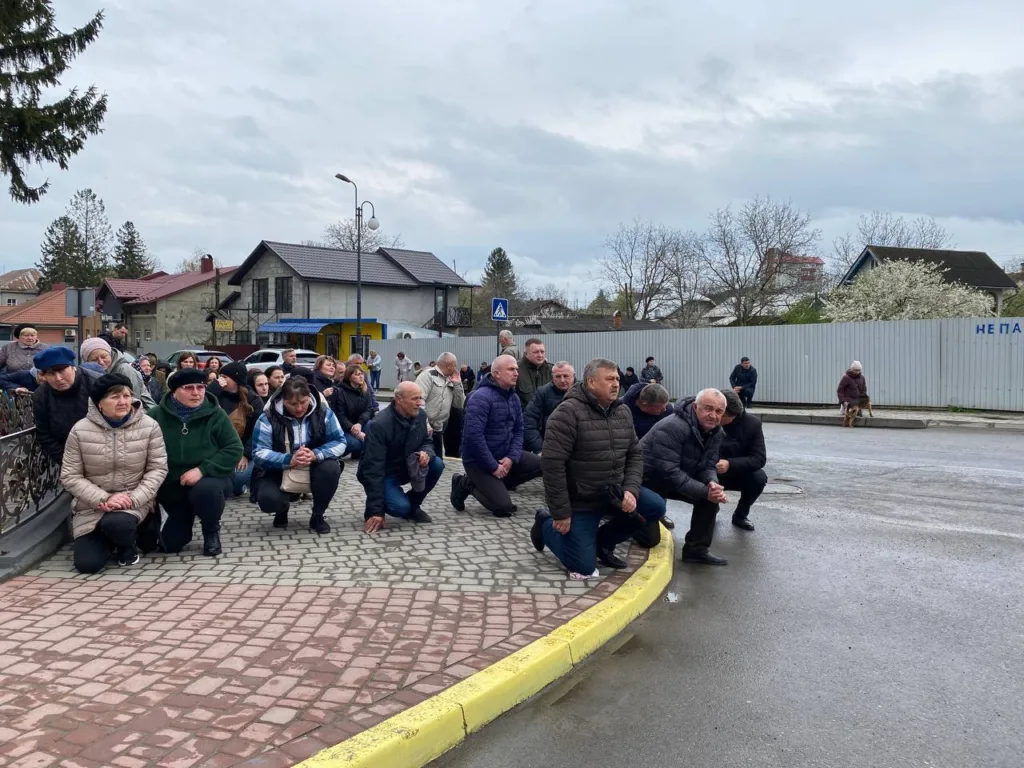 Люди на колінах уздовж дороги у місті