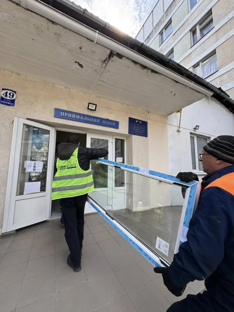 Робітники заносять вікно до приймального відділення лікарні
