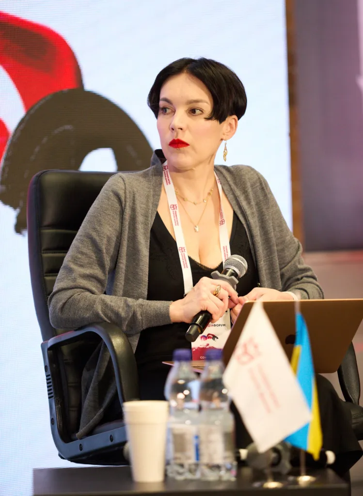 Жінка говорить на конференції, тримає мікрофон