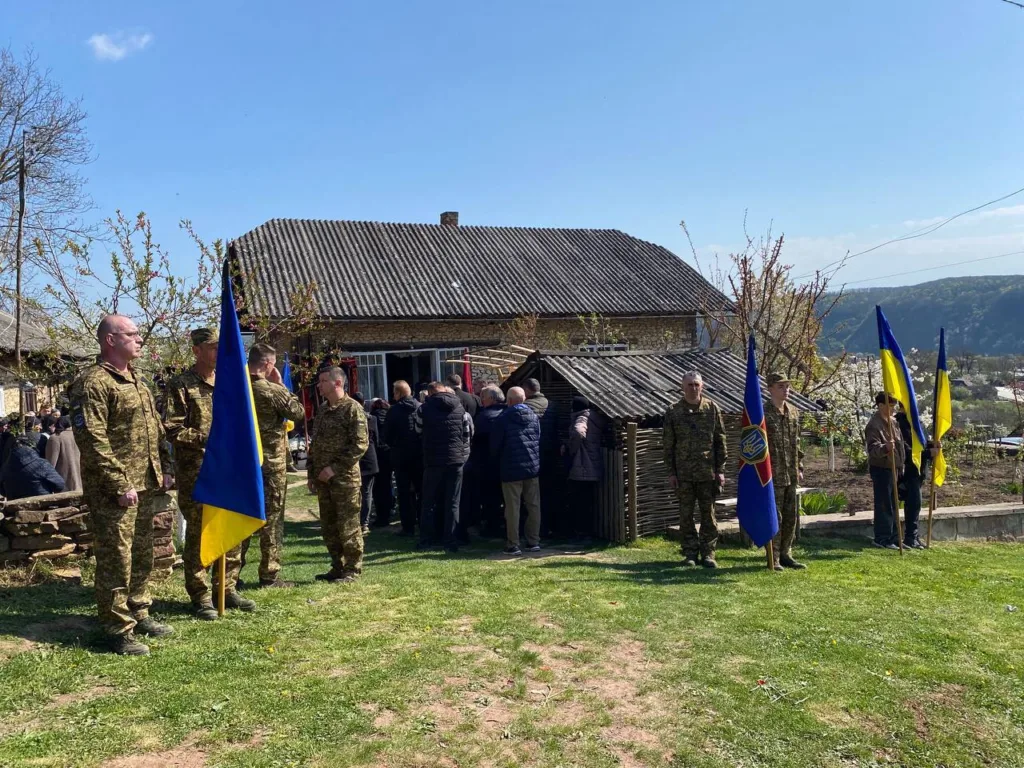 Військові з українськими прапорами біля сільського будинку