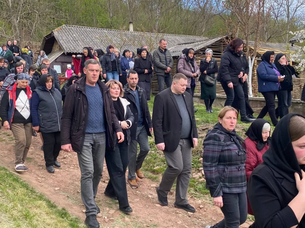 Люди йдуть селом під час похоронної процесії
