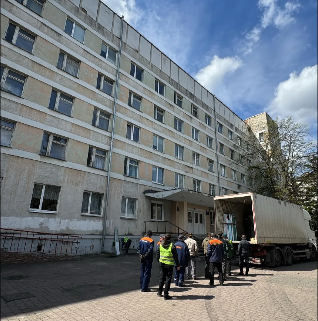 Працівники біля будівлі вантажать матеріали у вантажівку