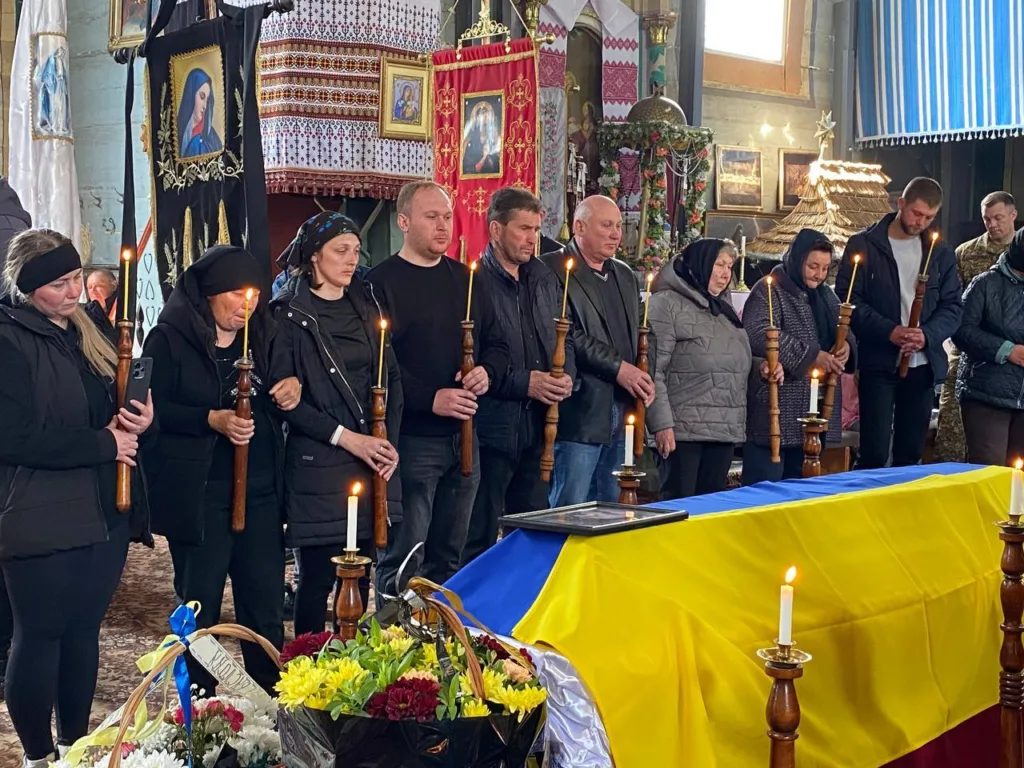 Люди прощаються із загиблим героєм під прапором України