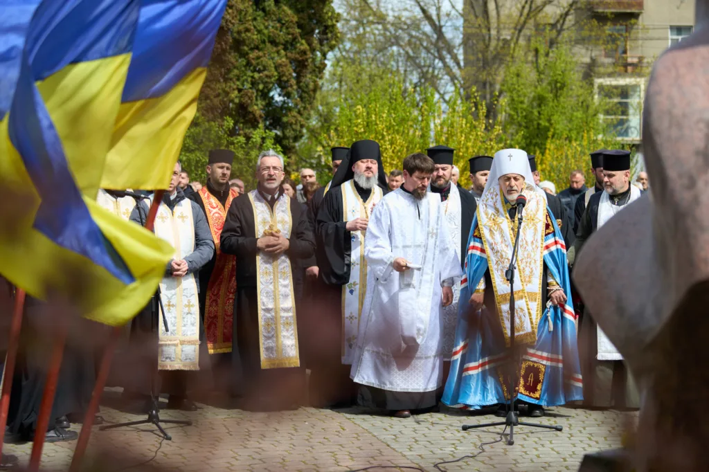 Священники моляться біля українського прапора на вулиці