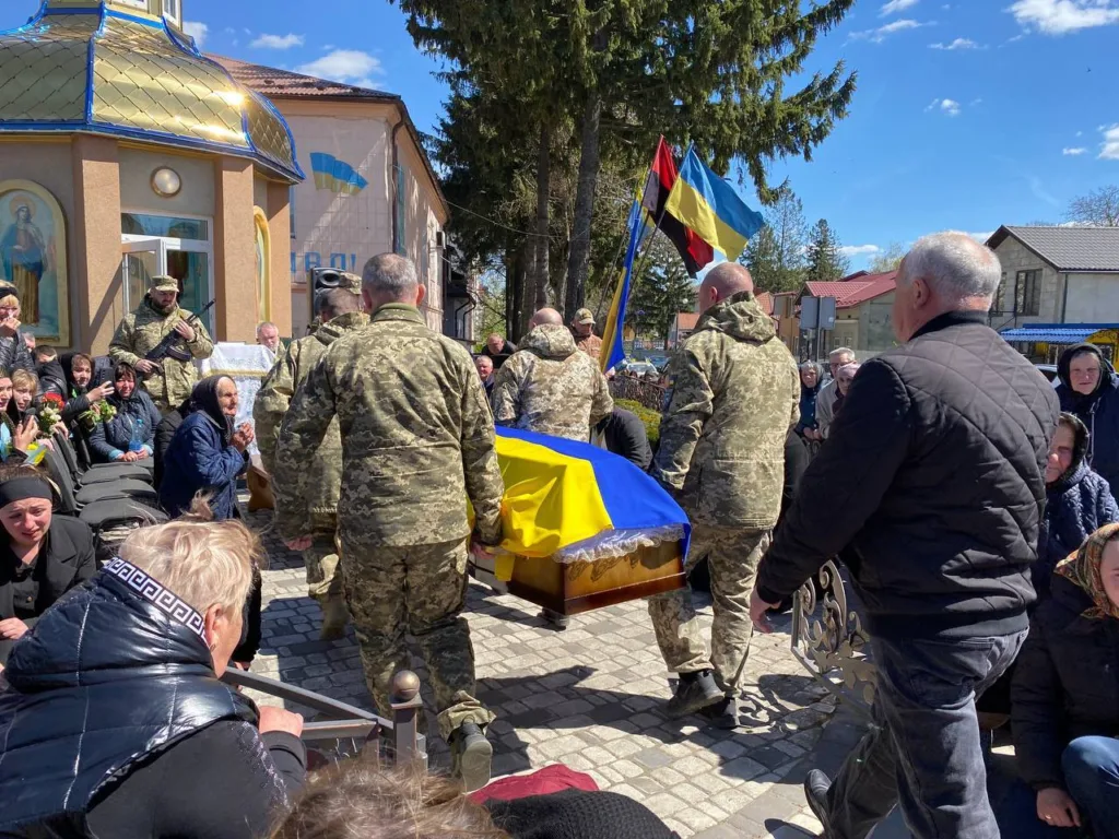 Військові несуть труну, накриту українським прапором