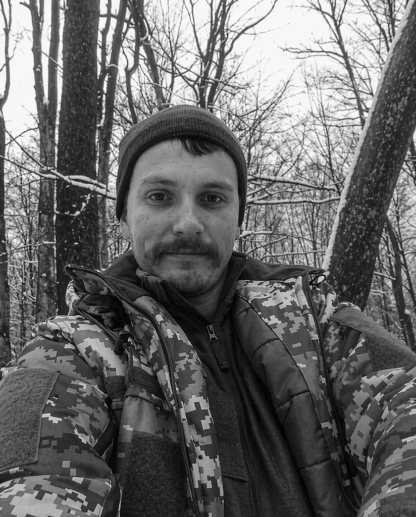 Чоловік у лісі взимку в камуфляжній куртці