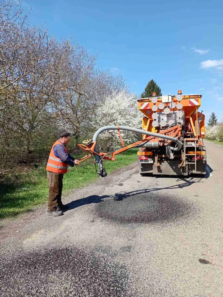 Робітник ремонтує дорожнє покриття спеціальною машиною