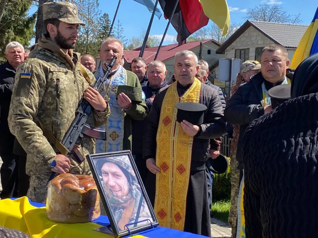 Військовий похорон із священиками та державними прапорами