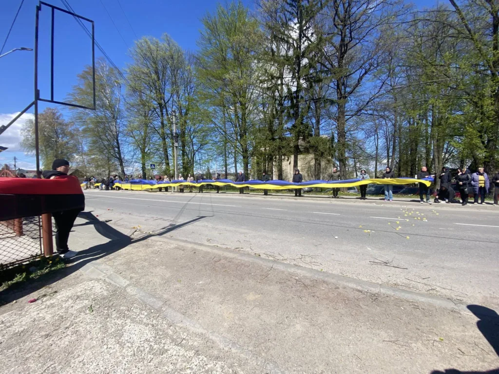 Люди тримають великий прапор України на вулиці