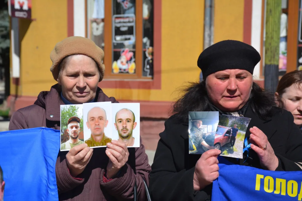 Жінки тримають фотографії зниклих військових на мітингу