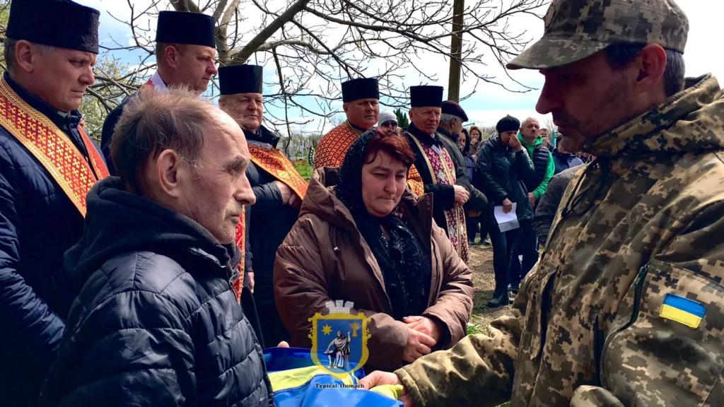 Військовий передає прапор родині загиблого героя
