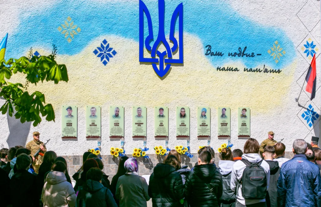 Люди вшановують загиблих героїв біля меморіальної стіни