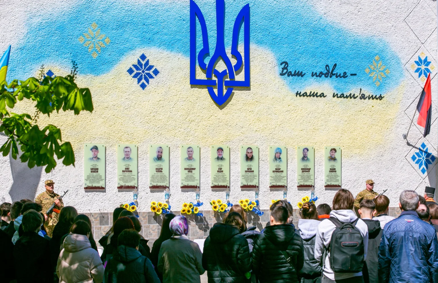 Люди вшановують загиблих героїв біля меморіальної стіни