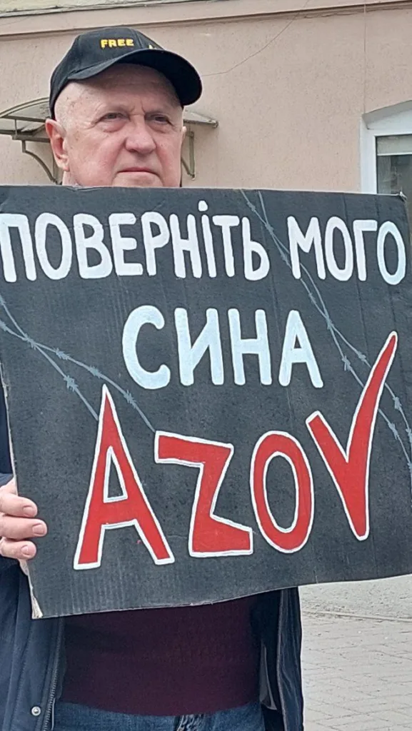 Чоловік тримає плакат із написом про Азов