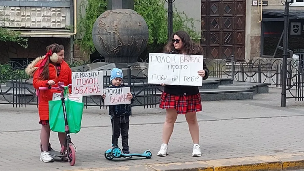 Люди стоять з плакатами на міській вулиці