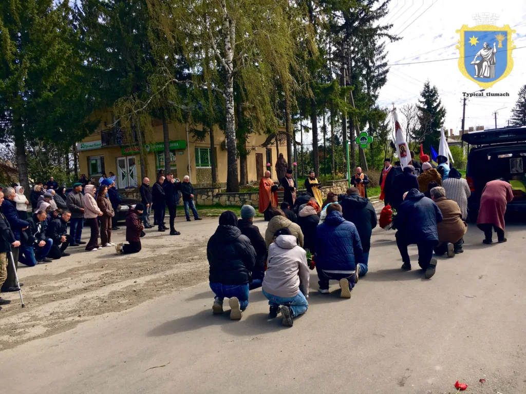 Люди на колінах під час похоронної церемонії