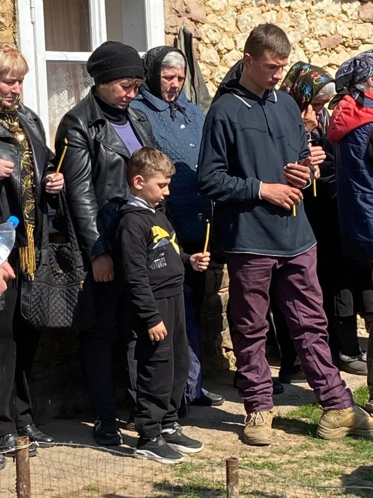 Люди стоять з восковими свічками на вулиці