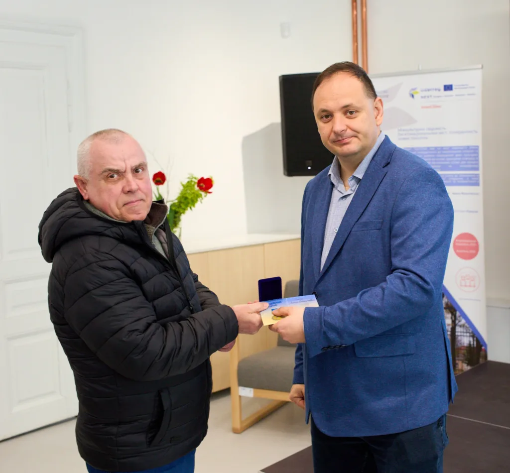 Вручення нагороди двома чоловіками у приміщенні