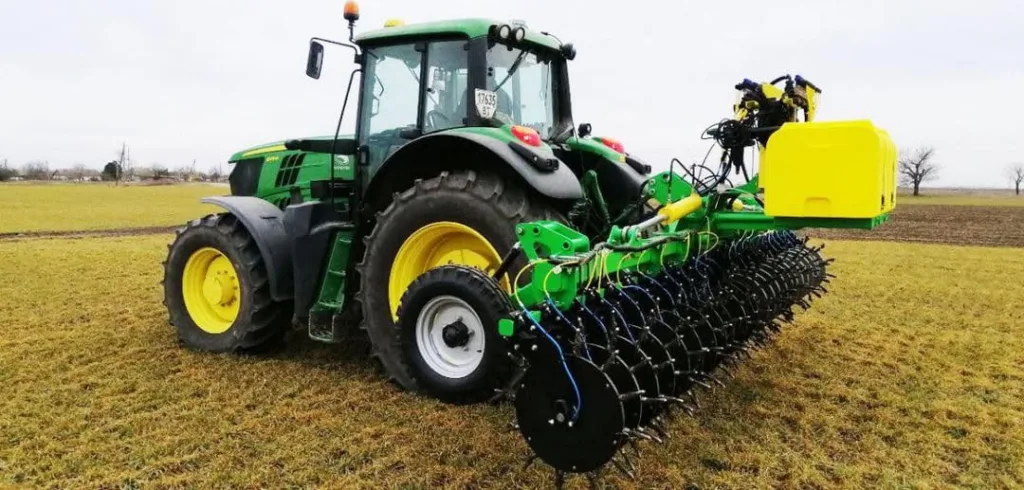 Зелений трактор із сільськогосподарським обладнанням у полі