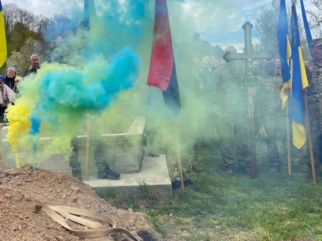 Військові з прапорами серед жовто-блакитного диму