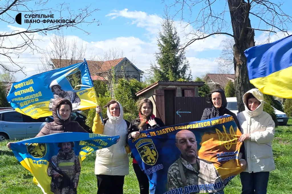 Люди тримають українські прапори та банери на вулиці