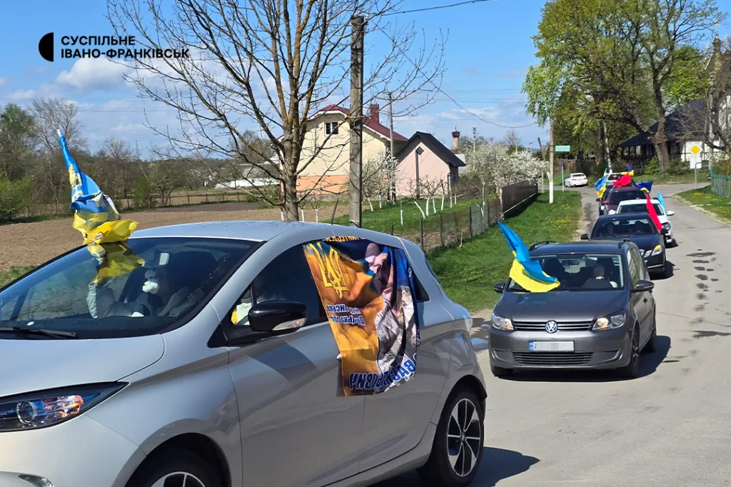 Автоколона з українськими прапорами на сільській дорозі