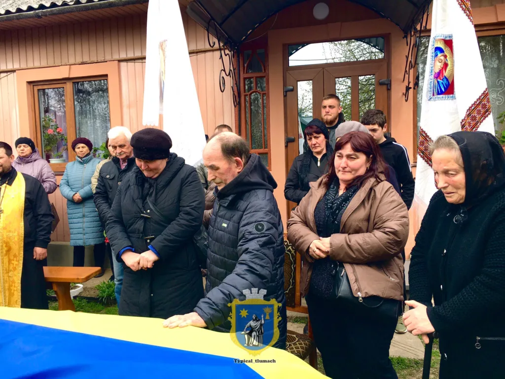 Люди моляться біля труни з українським прапором