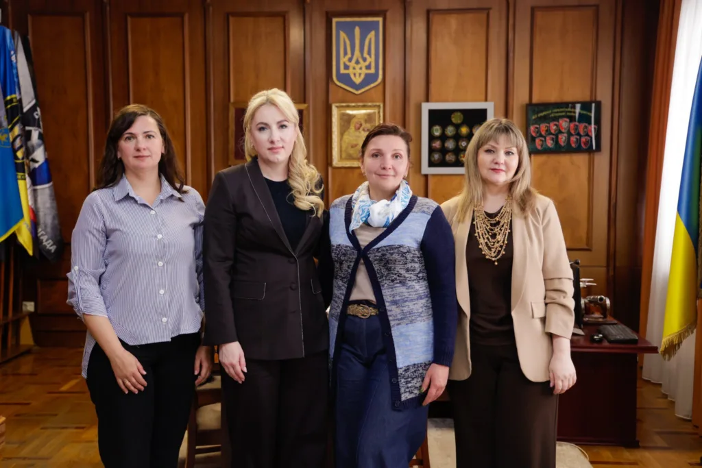 Чотири жінки в офісі перед українським прапором