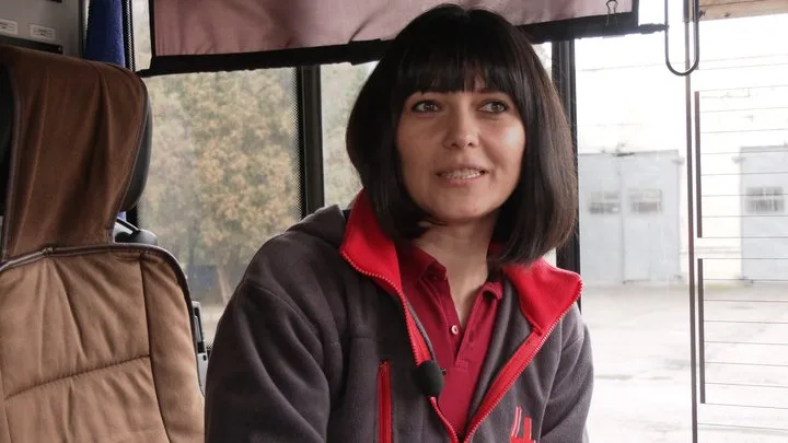 Жінка сидить у транспорті та посміхається