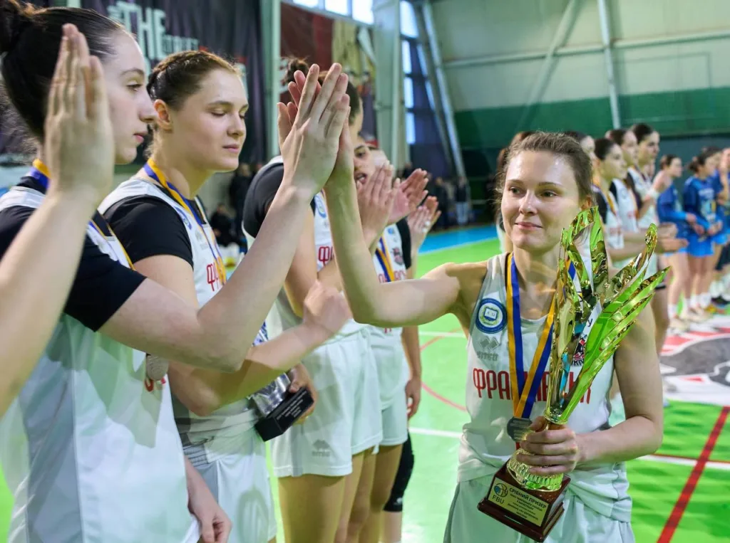 Жіноча баскетбольна команда святкує перемогу з трофеєм
