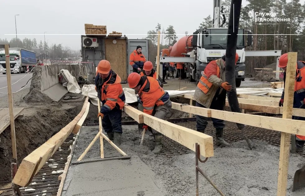 Будівельники заливають бетон на дорожньому майданчику