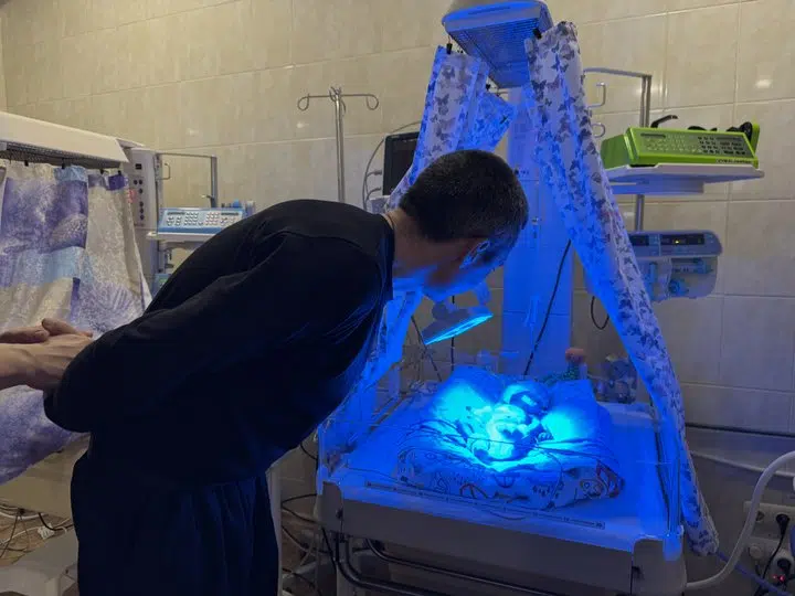 Батько спостерігає за немовлям під синім світлом